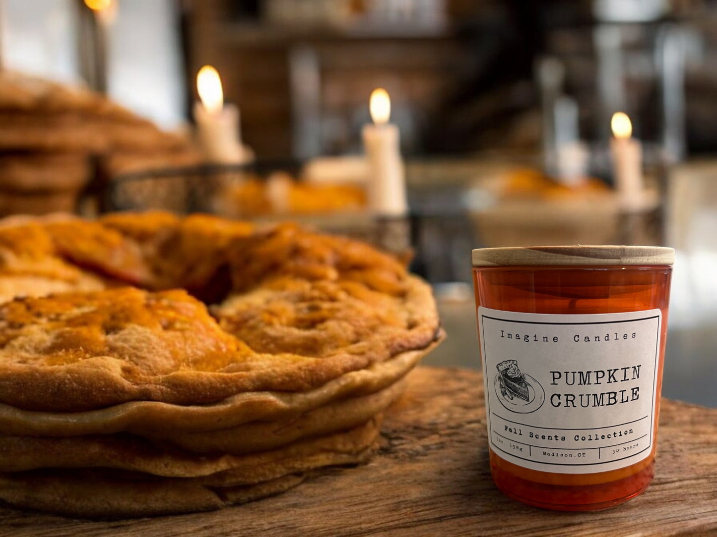 A Pumpkin Crumble candle on a bakery counter next to a pumpkin pie, evoking the warm, spicy aroma of a freshly baked pumpkin dessert with a buttery crumble topping.
