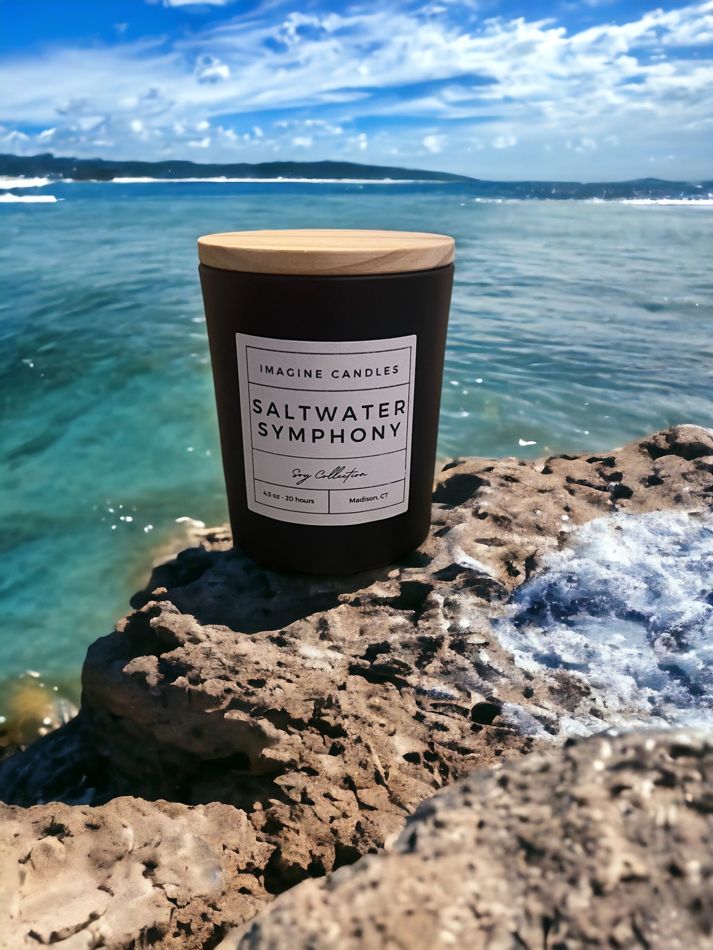 A candle sits along waves breaking on the shore, embodying the essence of Saltwater Symphony. The label reads 'Saltwater Symphony', evoking the sensation of water composing music and invigorating mind, body, and spirit. Fragrance notes include cardamom, orange peel, sea salt, light musk, palm, and amber, infused with natural essential oils, including cardamom, clove, and orange