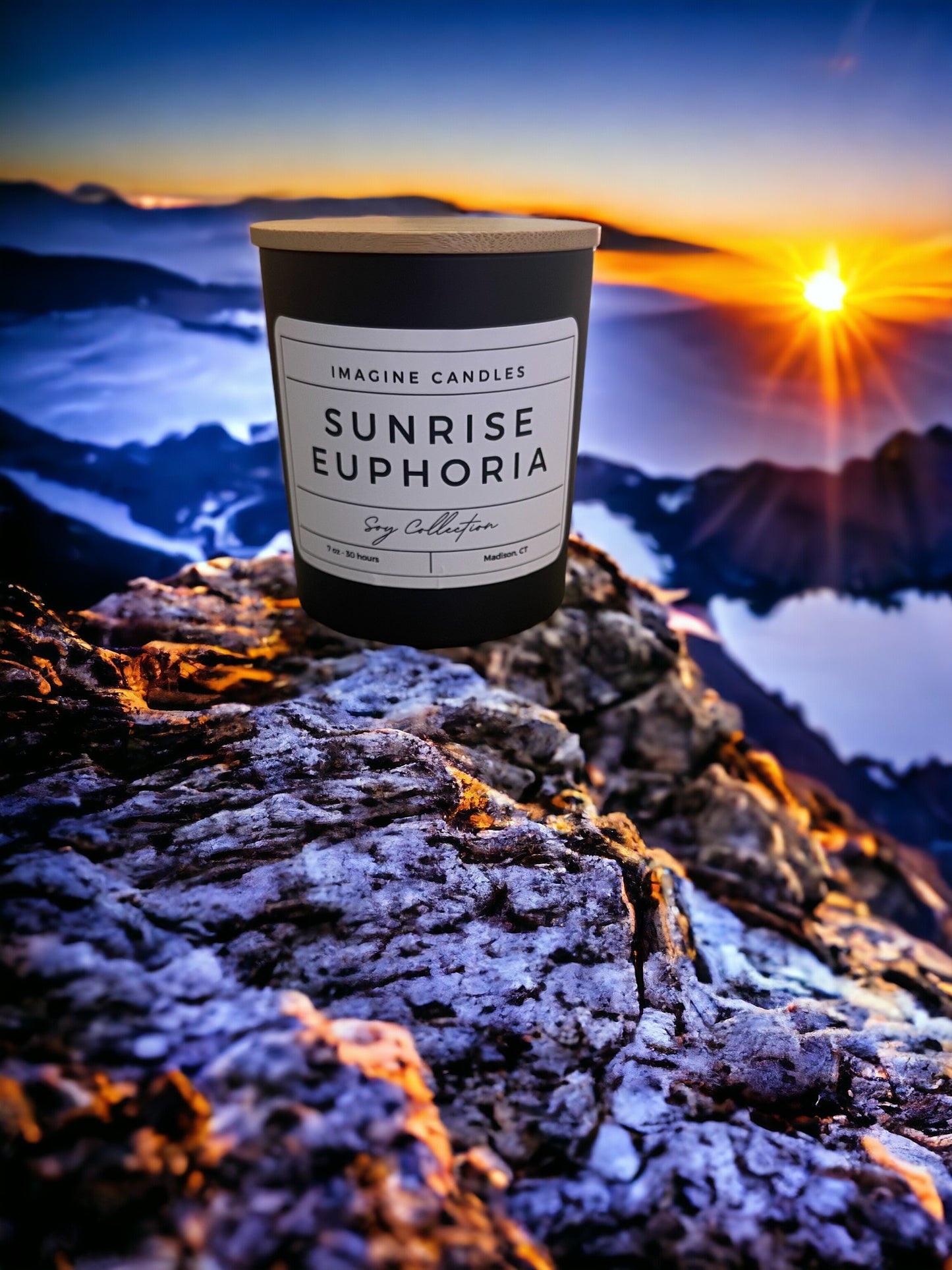 A candle sits atop a mountain at sunrise, embodying the essence of Sunrise Euphoria. The label reads 'Sunrise Euphoria', evoking the feeling of waking up early to a beautiful Saturday morning. Fragrance notes include orange, bergamot, coconut, gardenia, amber, vanilla, and musk