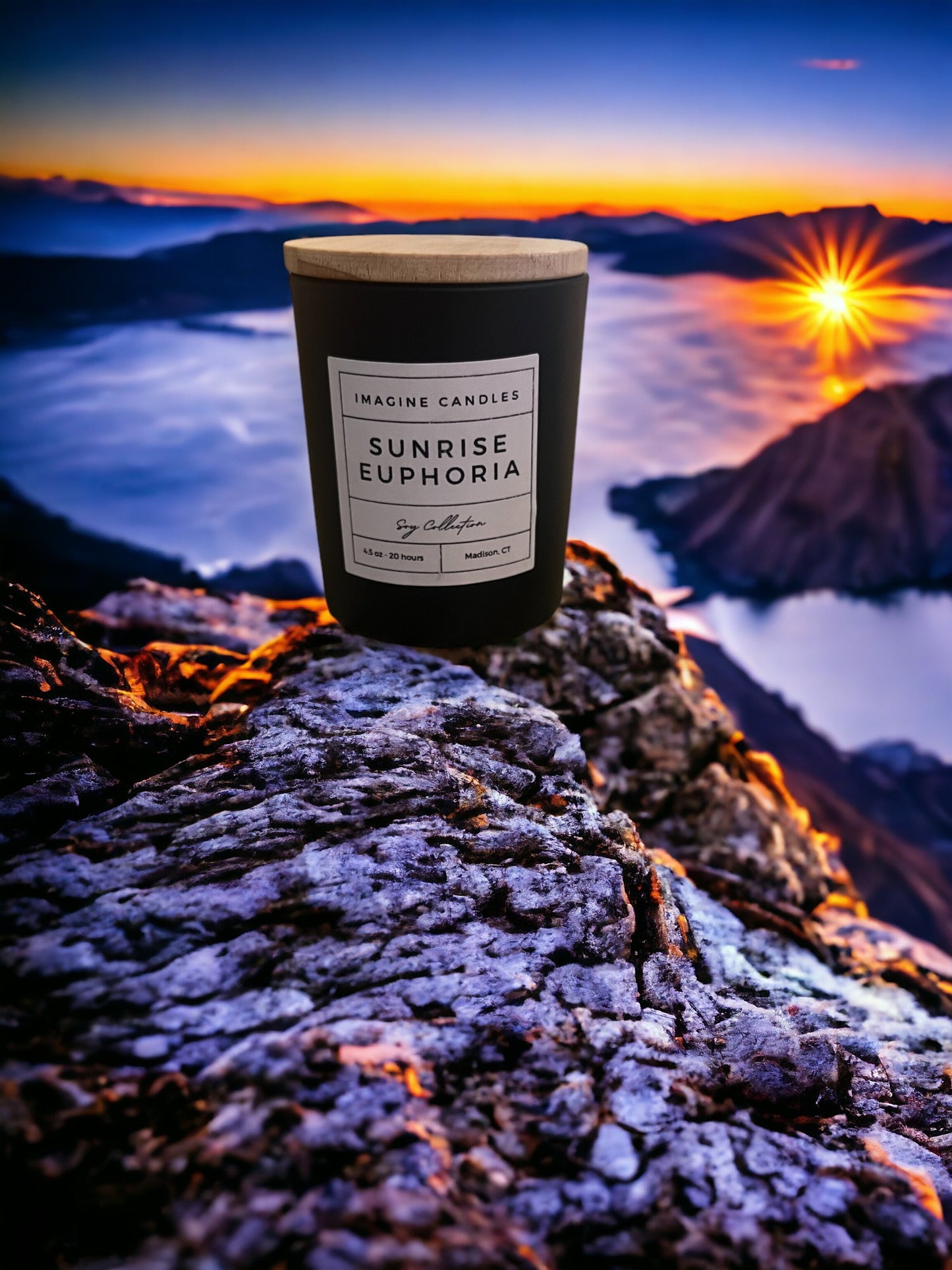 A candle sits atop a mountain at sunrise, embodying the essence of Sunrise Euphoria. The label reads 'Sunrise Euphoria', evoking the feeling of waking up early to a beautiful Saturday morning. Fragrance notes include orange, bergamot, coconut, gardenia, amber, vanilla, and musk