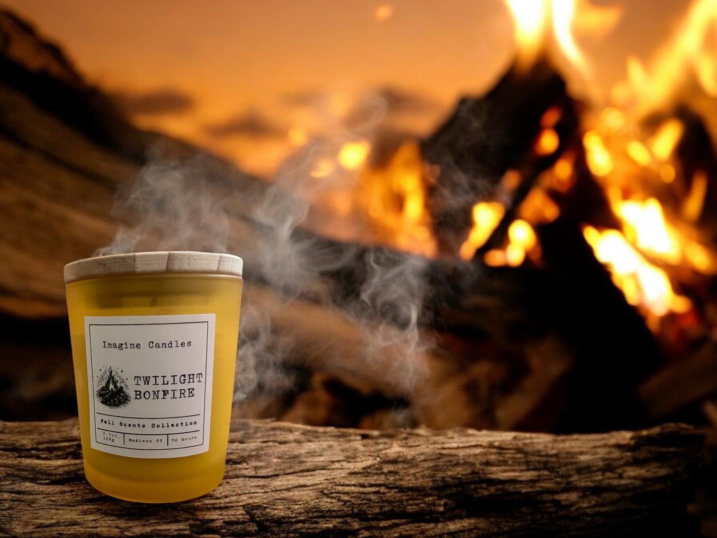 A candle sits on a log at a bonfire at dusk. Description: "Imagine a crackling campfire as the sun sets, casting a warm glow through the trees. Wrap yourself in the rich smoky embrace of Twilight Bonfire."