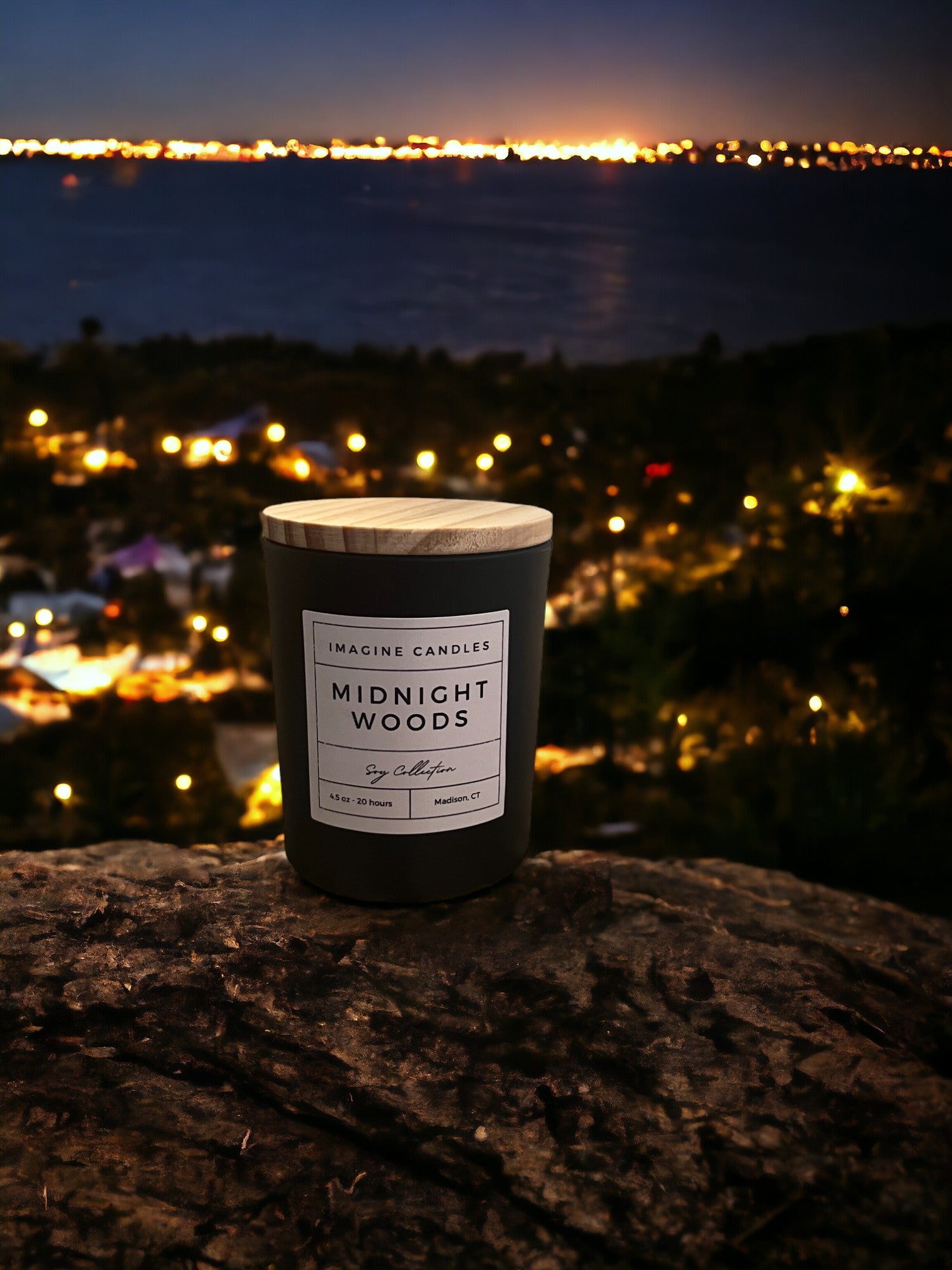 A candle overlooks a skyline at night, embodying the essence of Midnight Woods. The label reads 'Midnight Woods', evoking the feeling of staying up late watching an investigative thriller. The fragrance notes include citrus, plum, amber, jasmine, dark musk, amyris, and benzoin. Infused with natural essential oils, including cypress, cedarwood, patchouli, mandarine/tangerine, sweet orange, nootka tree, and davana