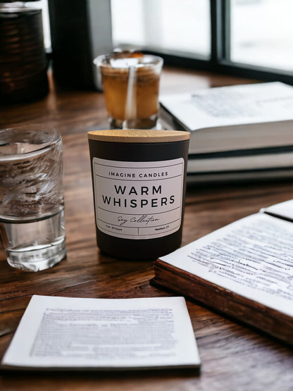 A candle sits on a table with a drink and a book, embodying the essence of Warm Whispers. The label reads 'Warm Whispers', evoking the feeling of excitement and energy. Fragrance notes include petitgrain, orange, grapefruit, cotton blossom, coconut, musk, powder, and wood, infused with natural essential oils, including orange peel, juniper, grapefruit peel, lemon peel, and tangerine."
